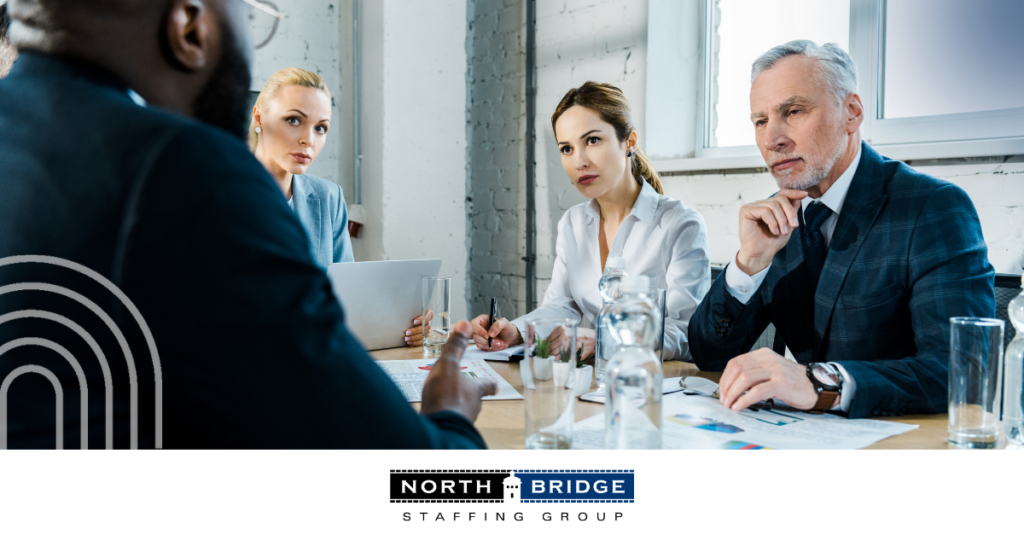 Three recruiters listen seriously during a panel interview for red and green flags.