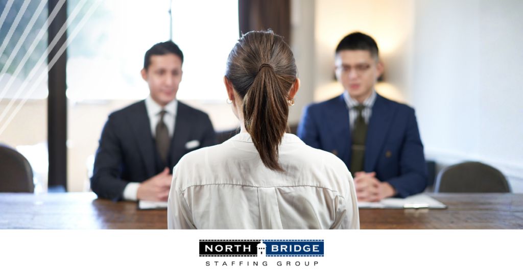 Job applicant viewed from behind sits facing two interviewers