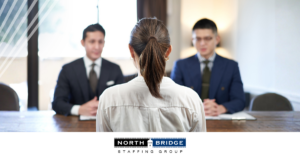 Job applicant viewed from behind sits facing two interviewers