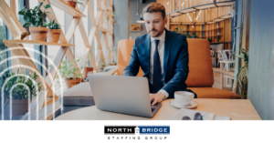 Professional sits at a coffee table, working on a laptop, symbolizing skills and fit