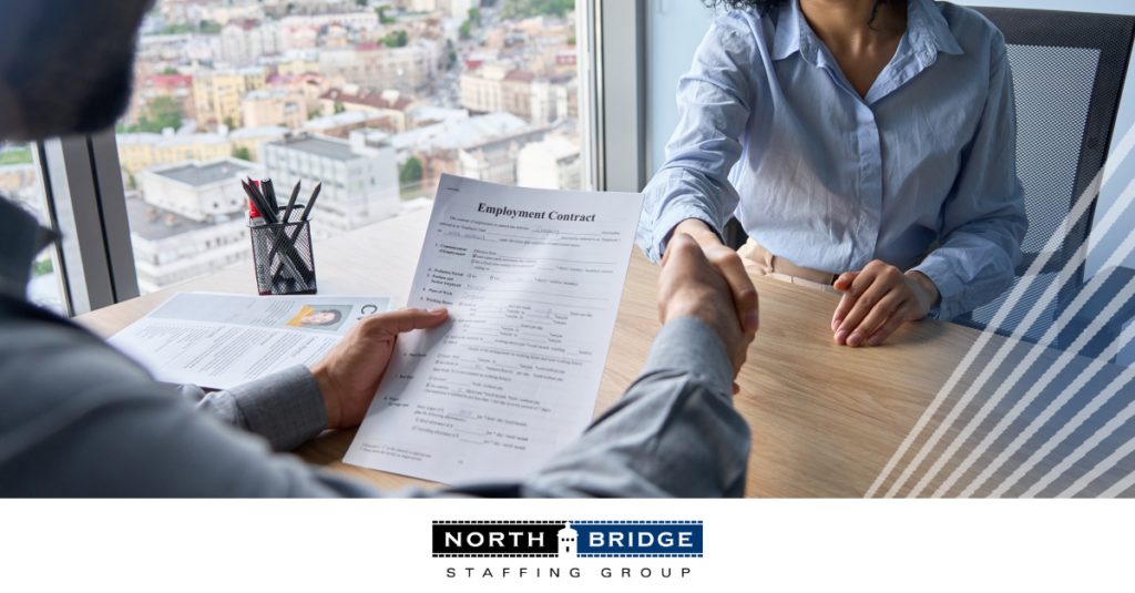 A candidate holds an employment contract while shaking hands with a recruiter, symbolizing a successful staffing partnership.
