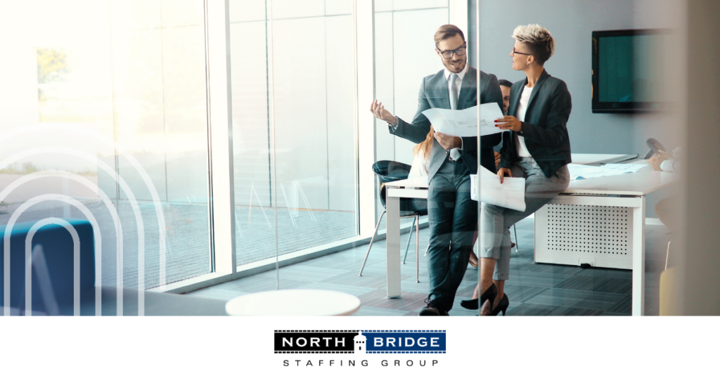 Two professionals discuss papers in an office, illustrating successful relationship-first recruiters.