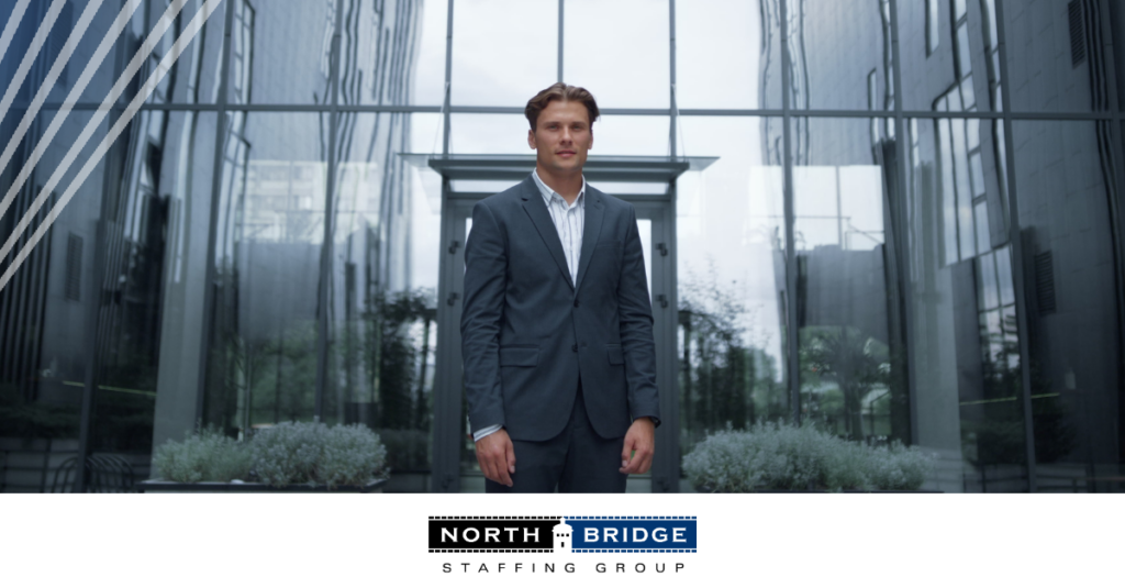 Professional in business attire stands alone in front of a glass building, representing talent in a competitive market