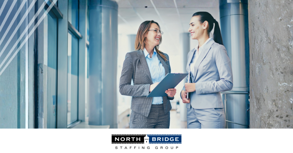 Two professionals stand smiling, one holding a clipboard, symbolizing a long-term recruiting partnership