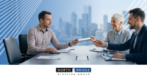 Three professionals pass a tablet around, one looking concerned, illustrating internal misalignment that can derail a hiring search.
